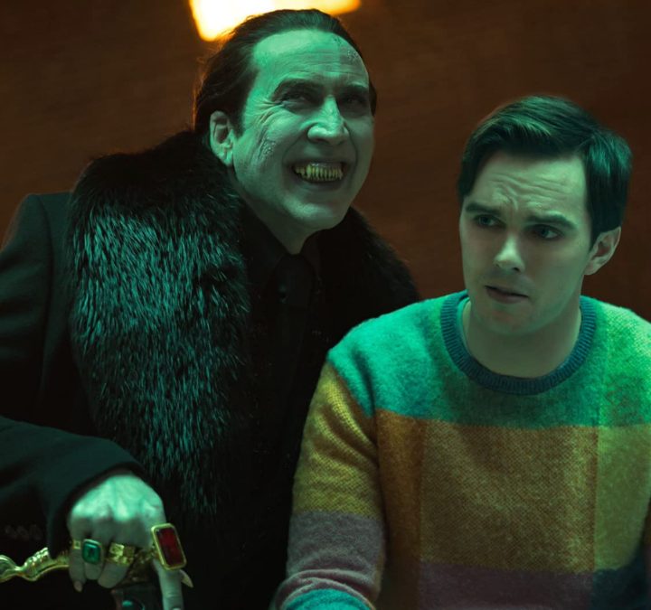 Dracula stands over a man sitting down in a scene from Renfield.