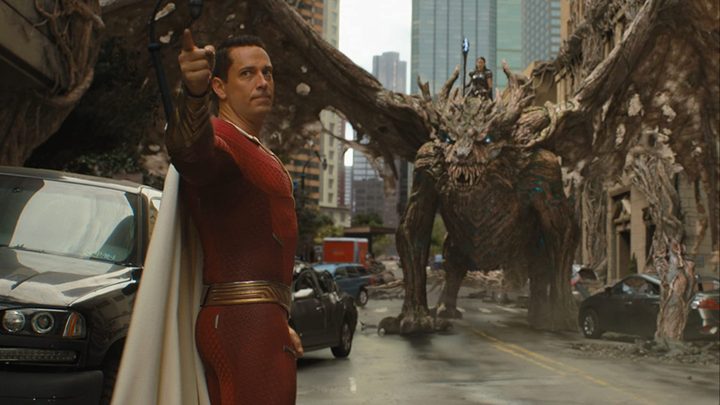 Zachary Levi as Shazam points with a dragon behind him in Shazam! Fury of the Gods.