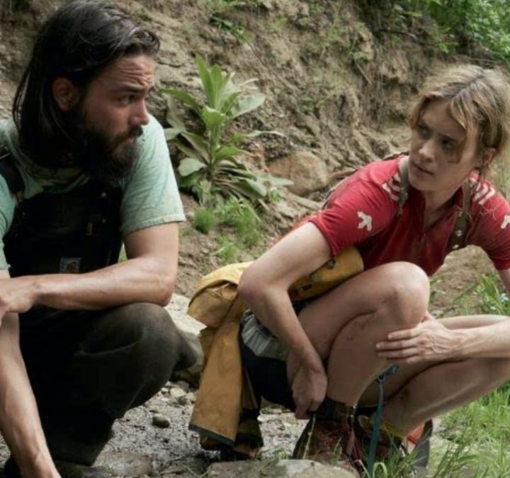Two people stand at the base of a creek in Station Eleven.