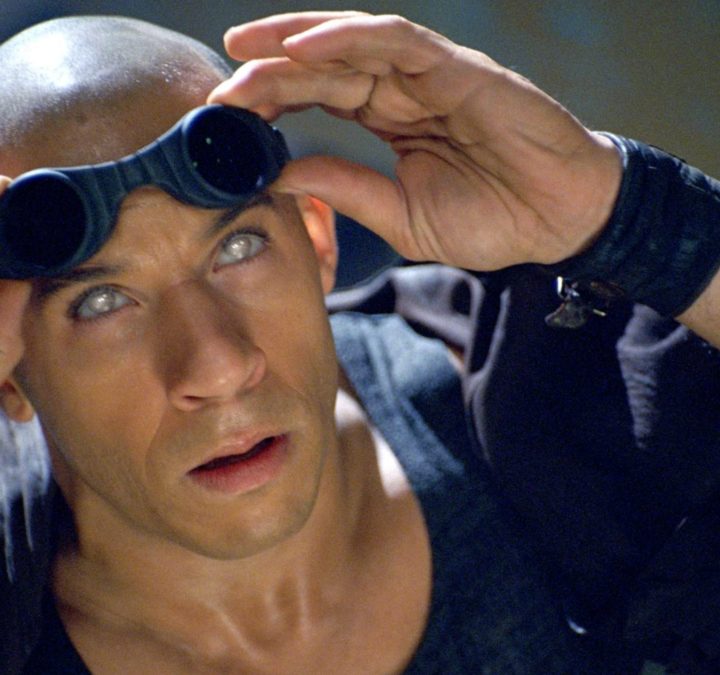 Vin Diesel's Riddick holds up his glasses in The Chronicles of Riddick.