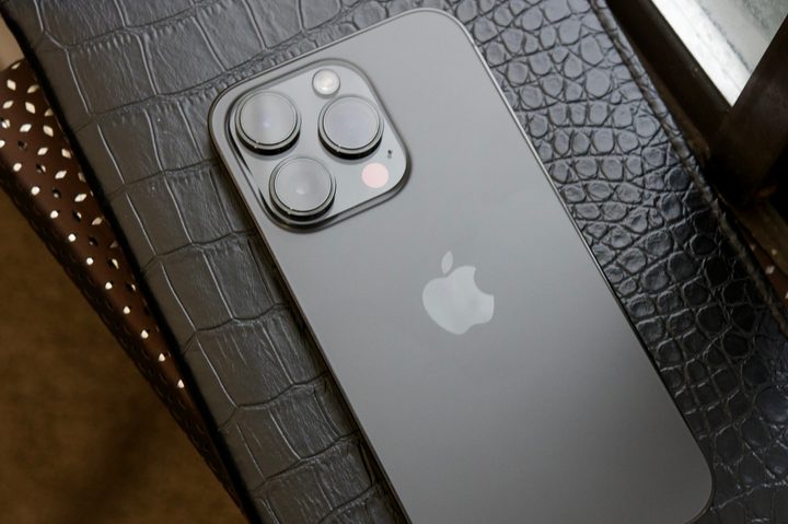 A black iPhone 14 Pro laying face-down on a black journal.