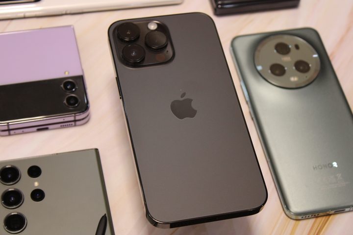 iPhone 14 Pro Max with Honor Magic 5 Pro and Galaxy Z Flip 4 in background.