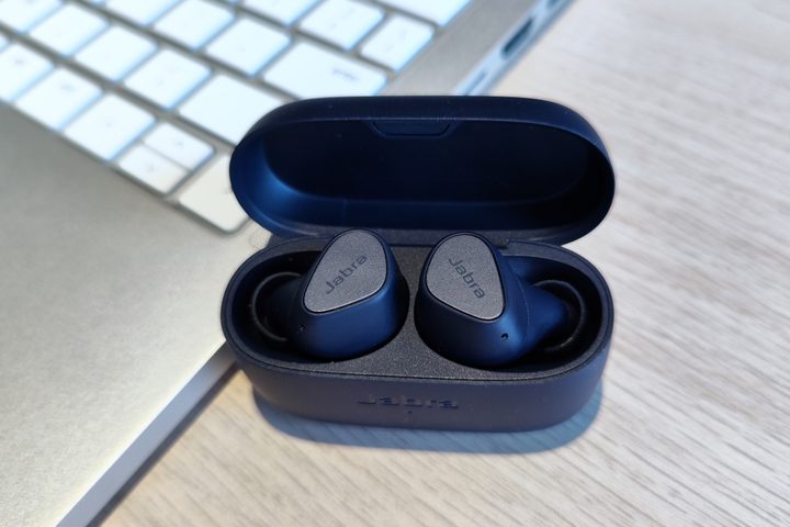 Jabra Elite 4 sitting beside laptop, inside open charging case.