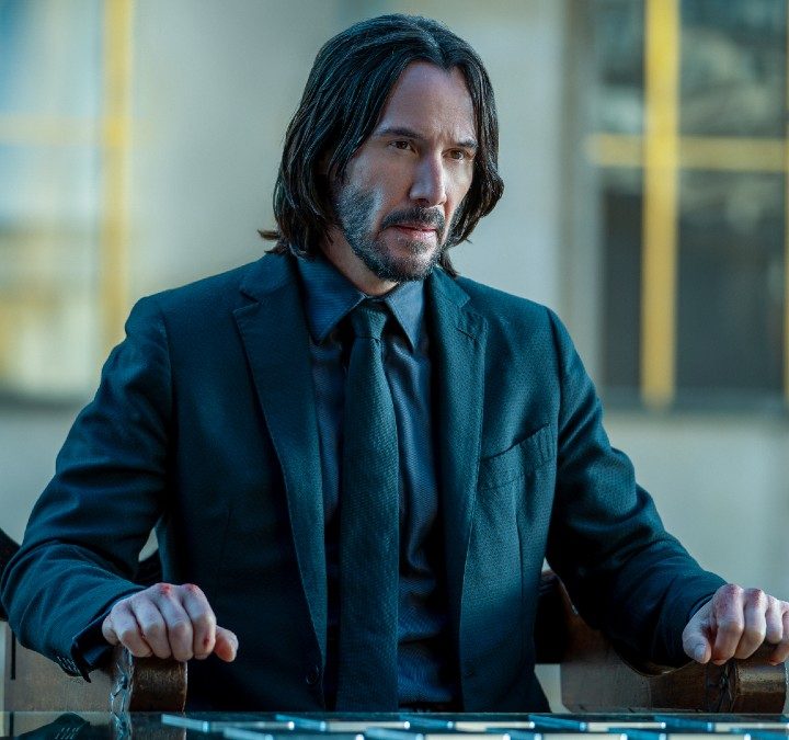 John Wick sits at a table.