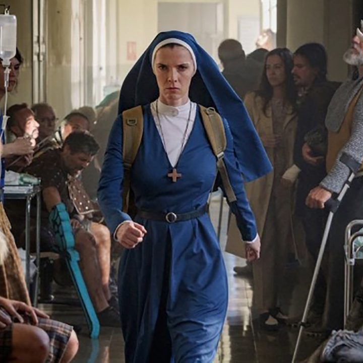 Betty Gilpin dressed as a nun, walking as people look on, looking determined and angry in a scene from Mrs. Davis on Peacock.