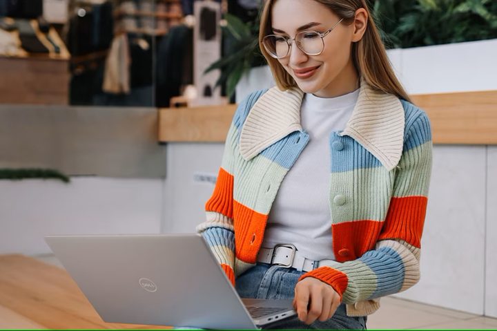 A woman using a Dell Inspiron 14 laptop.