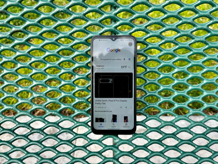 Samsung Galaxy A14 5G showing Google news on a park bench