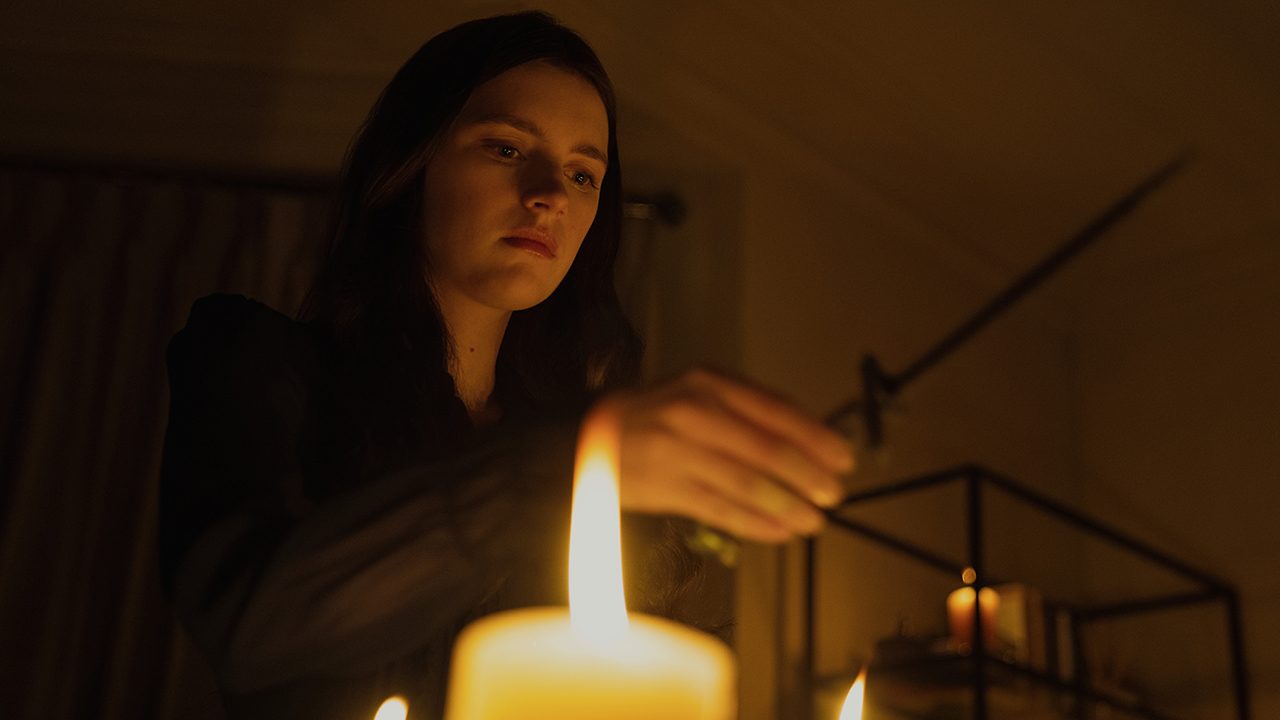 Leanne lighting candles in a scene from Servant.