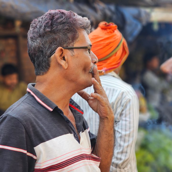 Man smokes while standing in a flower market captured with the Samsung Galaxy S23 Ultra’s 3x telephoto portrait mode camera.