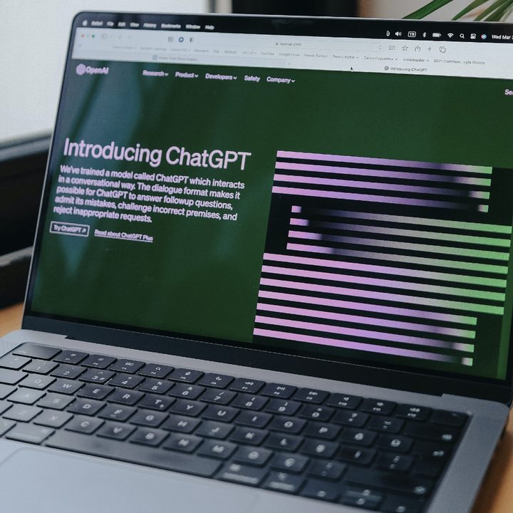 A MacBook Pro on a desk with ChatGPT's website showing on its display.