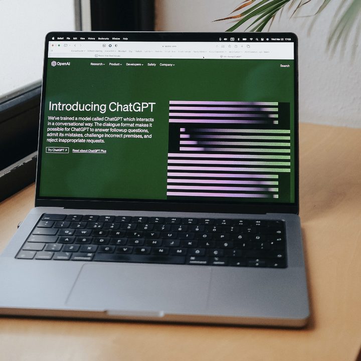 A MacBook Pro on a desk with ChatGPT's website showing on its display.