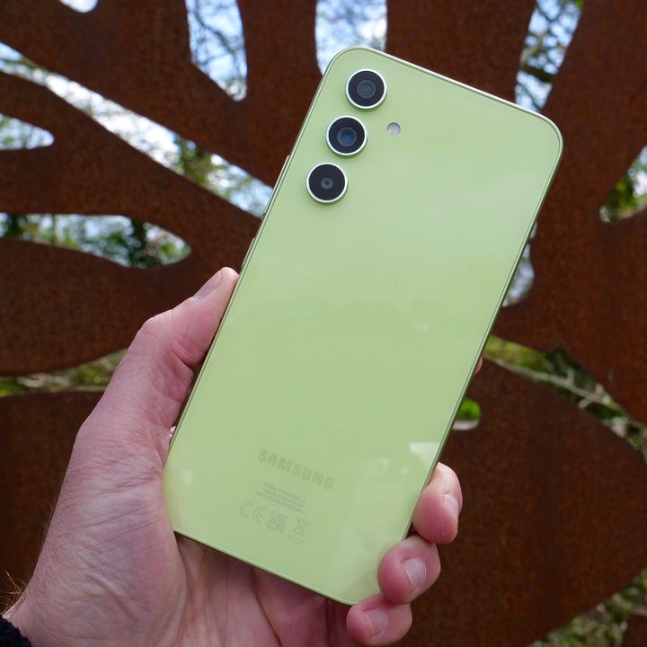 A person holding the Samsung Galaxy A54, showing the back.