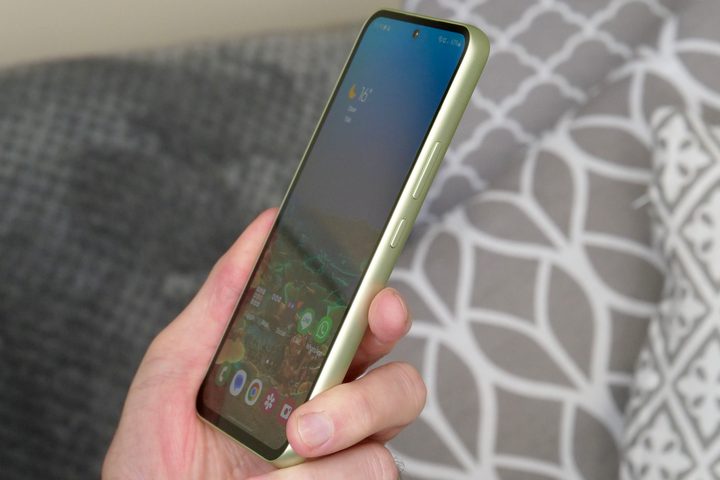 A person holding the Samsung Galaxy A54, seen from the side.