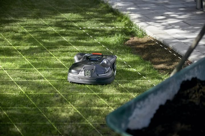 A Husqvarna robot lawn mower on a lawn with a grid draw on the grass.