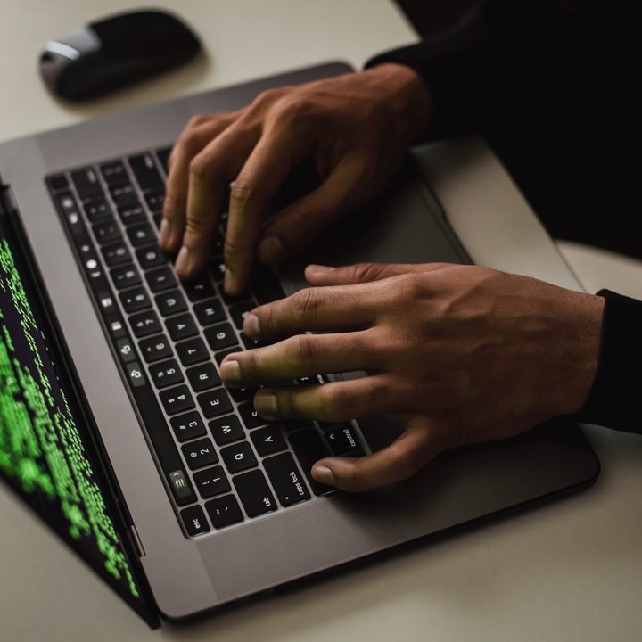 A person using a laptop with a set of code seen on the display.
