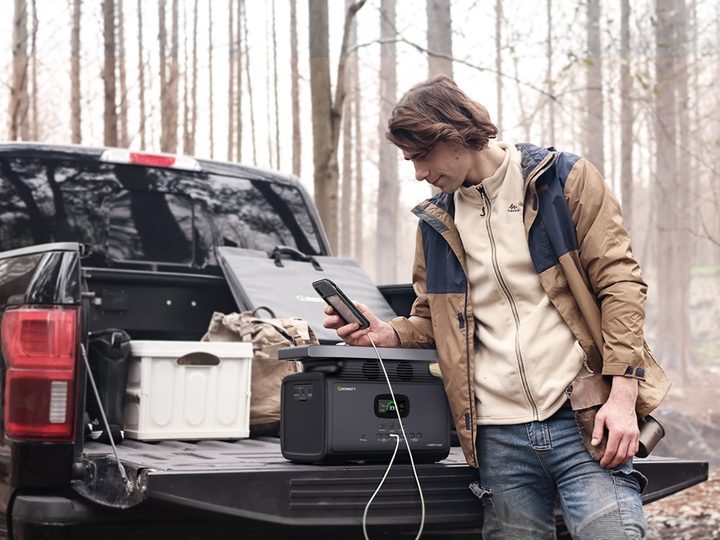 Man using INFINITY 1300 while camping to charge phone