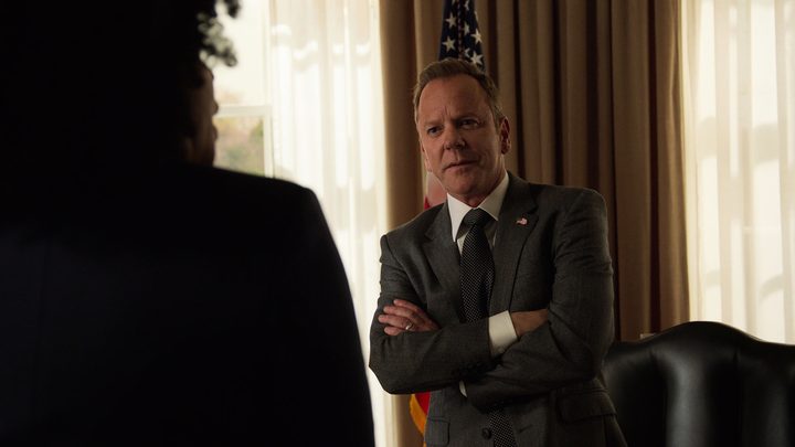 Kiefer Sutherland as Thomas Kirkman standing in his office with his arms folded in a scene from Designated Survivor.