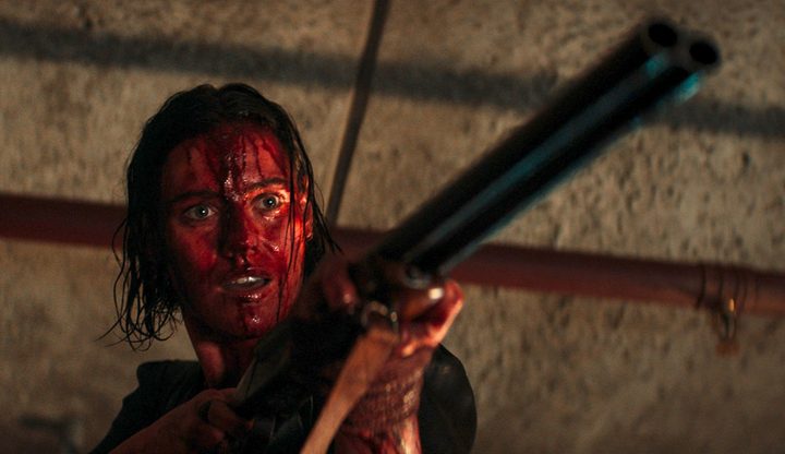 A woman aims a shotgun in Evil Dead Rise.