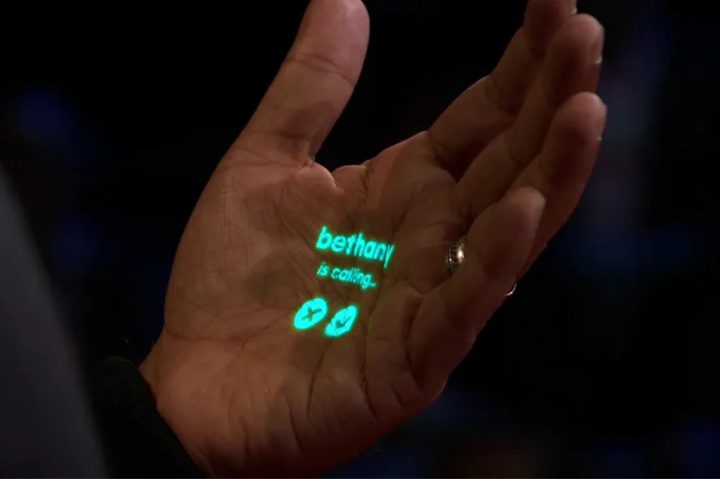 A demo of Humane's wearable, projecting an incoming phone call onto someone's hand.