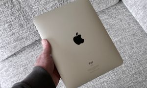 A person holding an original iPad, showing the back.