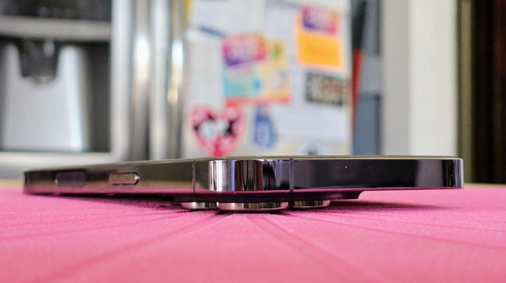 A Deep Purple iPhone 14 Pro on a table showing that the camera bump makes it impossible to lay flat