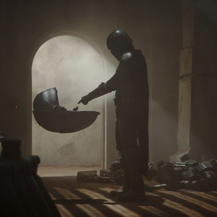 A screenshot from the first episode of The Mandalorian, showing the Mandalorian when he first sees Grogu.