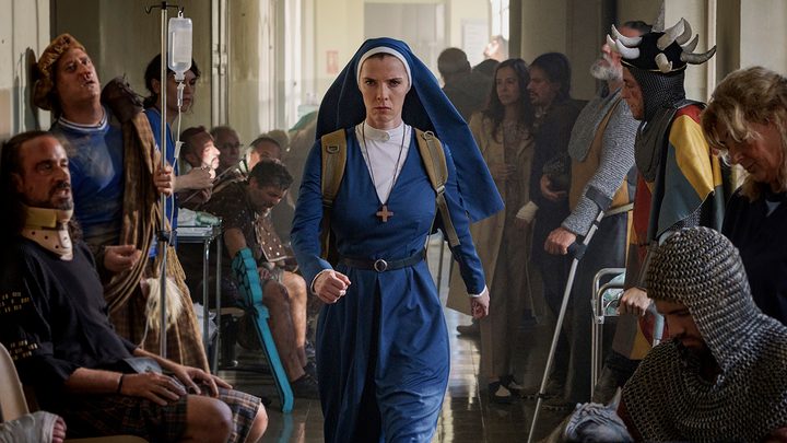Simon in her habit walking through a crowd of people looking angry in Mrs. Davis on Peacock.