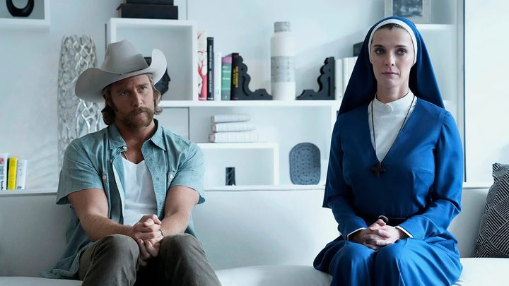 A nun and a man sit on a couch in Mrs. Davis.