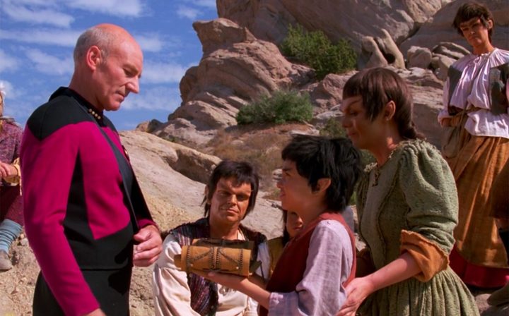 Picard interacts with an alien family in Star Trek: The Next Generation.