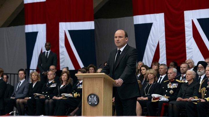 Prime Minister Trowbridge standing at a podium in a scene from The Diplomat on Netflix.