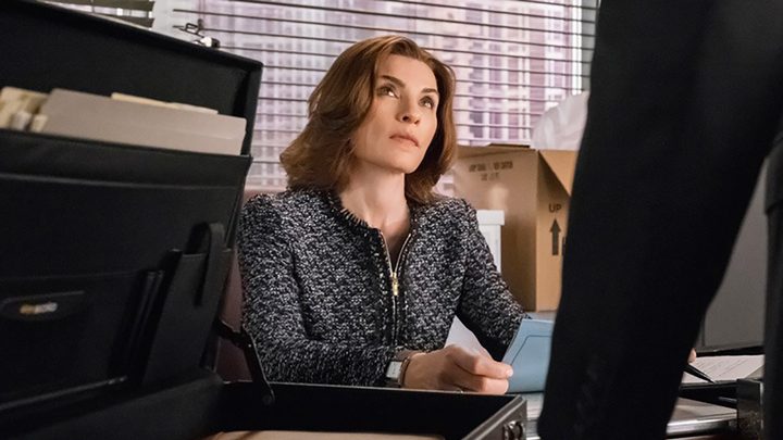 A woman sits behind her desk looking up at a man speaking to her in a scene from The Good Wife.