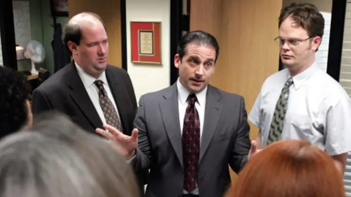 Characters from The Office around Michael Scott talking.