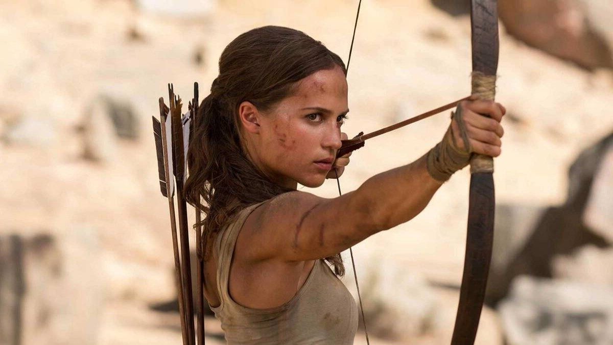Alicia Vikander as Lara Croft holds a bow and arrow in Tomb Raider.