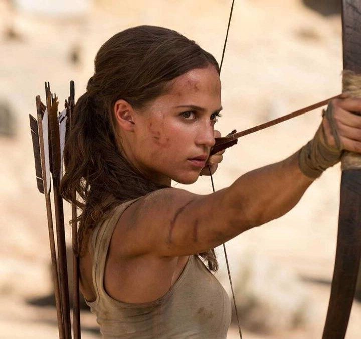 Alicia Vikander as Lara Croft holds a bow and arrow in Tomb Raider.