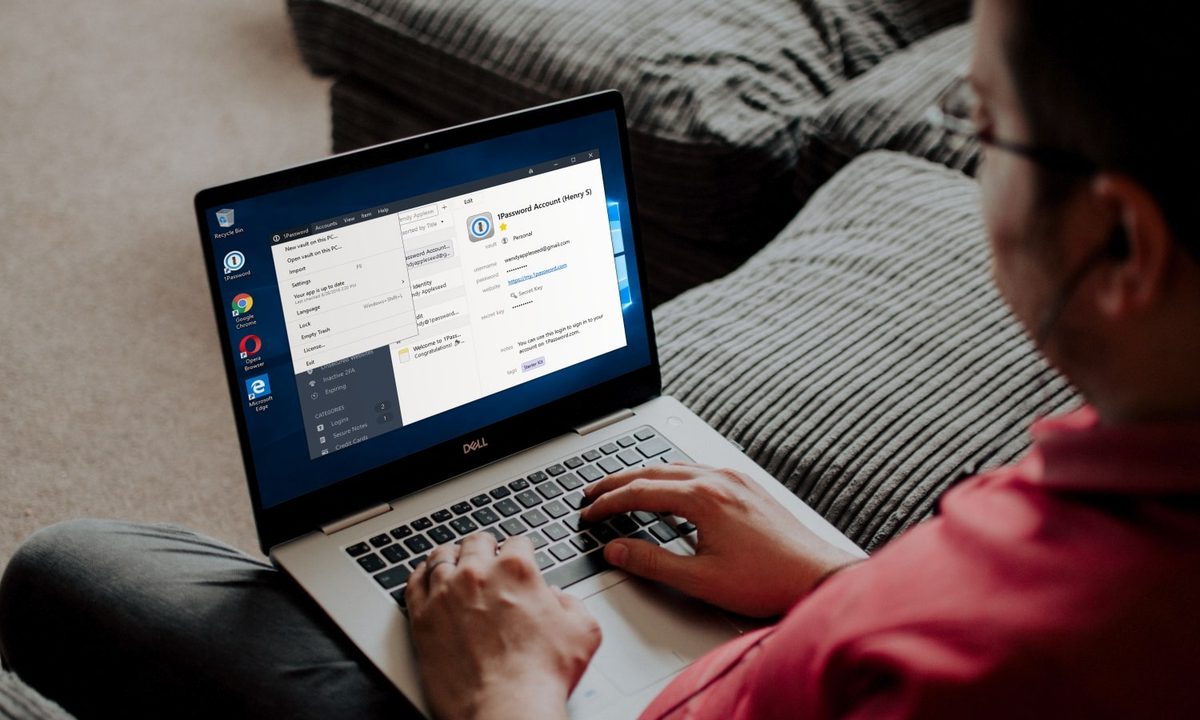 A person using the 1Password password manager on a laptop while sat on a couch.