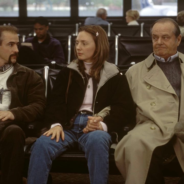 Three people sit down next to each other at the airport.