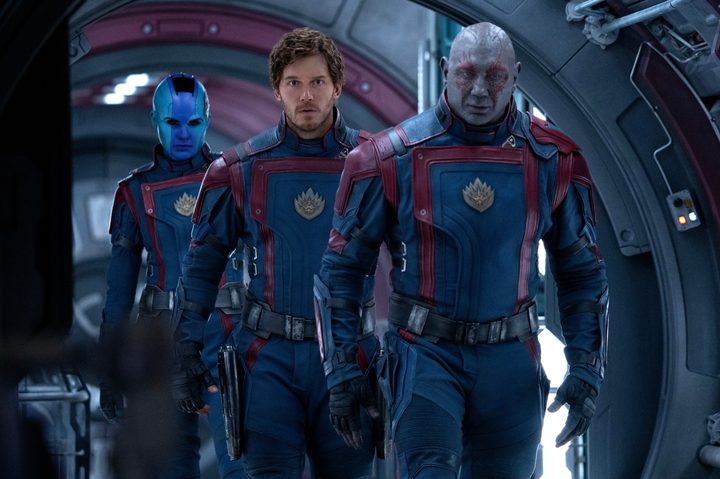 'Guardians of the Galaxy Vol. 3' Nebula (Karen Gillan), Star-Lord (Chris Pratt), and Drax (Dave Bautista) wearing black and red uniforms, walking along a metal ship hallway.