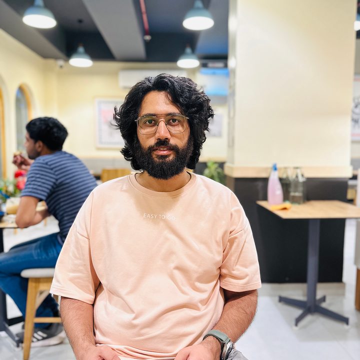 Portrait shot of a man sitting in a cafe captured by the iPhone 14 Pro.