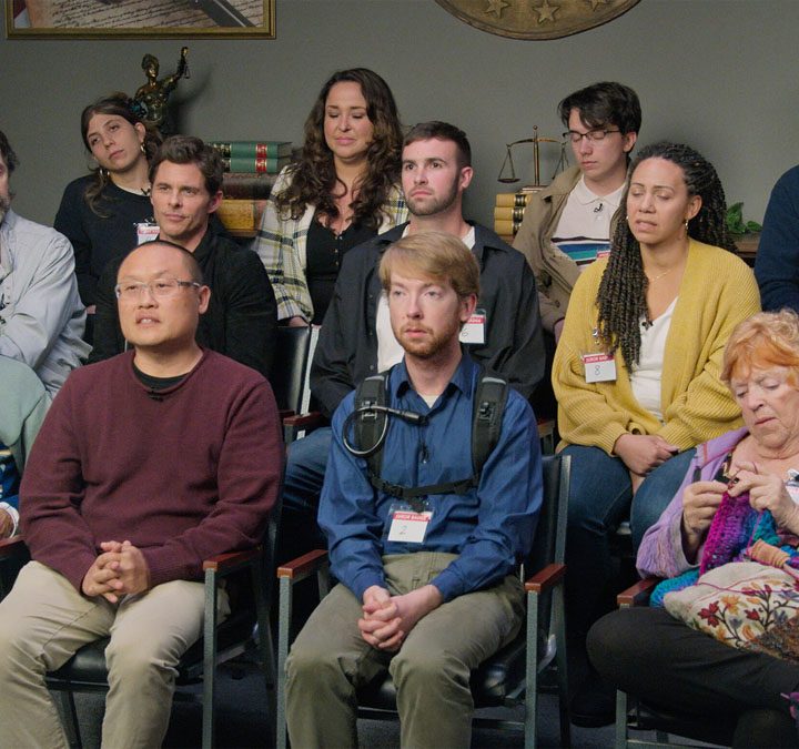 The cast of Jury Duty sitting together and looking intently.