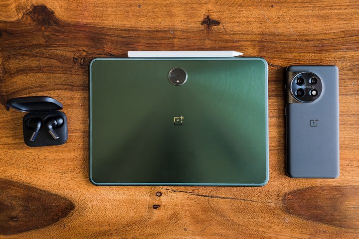 Green OnePlus Pad Android tablet, gray OnePlus 11, and black OnePlus Buds Pro 2 on a wooden table.