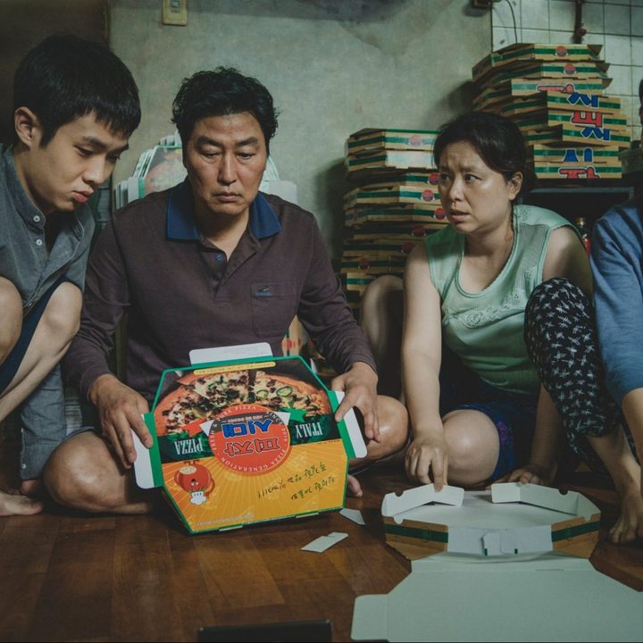 The Kim family gathers around a pizza box in a still from the movie Parasite.