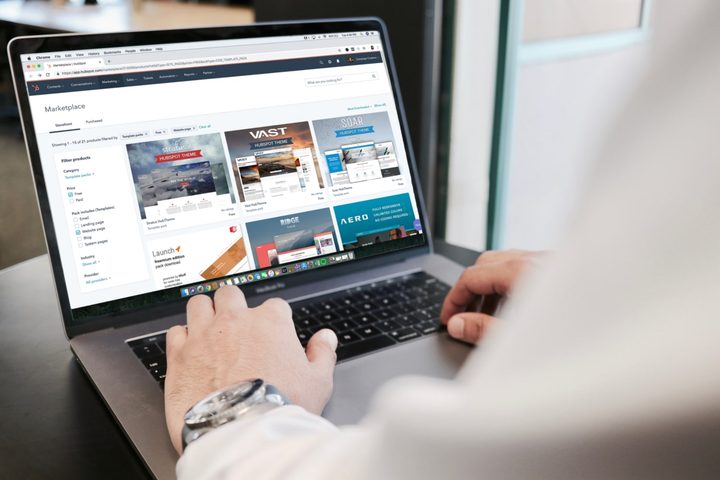 A person using a laptop on a desk with a web browser showing the HubSpot marketplace on their screen.