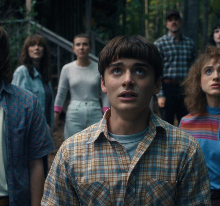 The cast of "Stranger Things" stand next to each other and look up.
