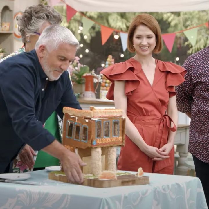 A group of judges stand around a cake in The Great American Baking Show.