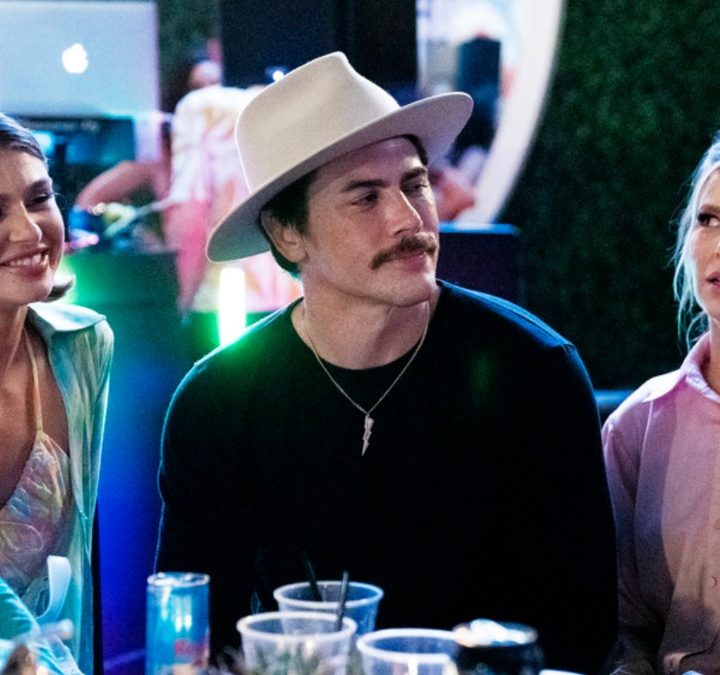 Three people sit next to each other at a table on Vanderpump Rules.
