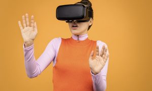 A woman wearing a virtual reality headset against an orange background.