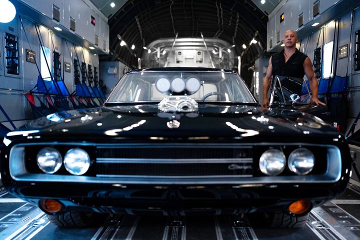 A man stands next to a car in Fast X.