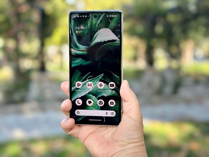 Google Pixel 7a held in hand showing home screen