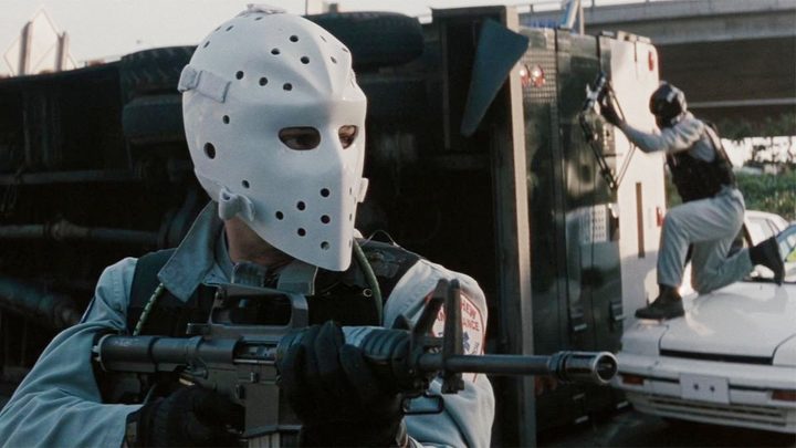 An armed robber holds a gun in Heat.