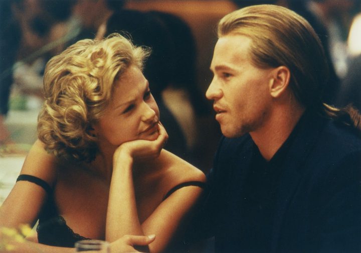 A woman looks at a man at dinner in Heat.